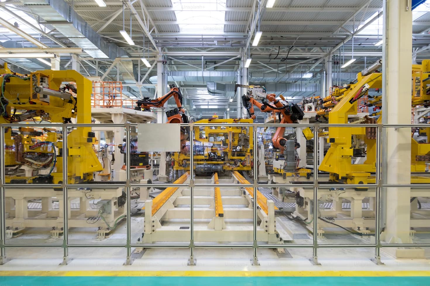 Celda de manufactura discreta con robots industriales y estaciones de ensamble protegidas por guardas de seguridad